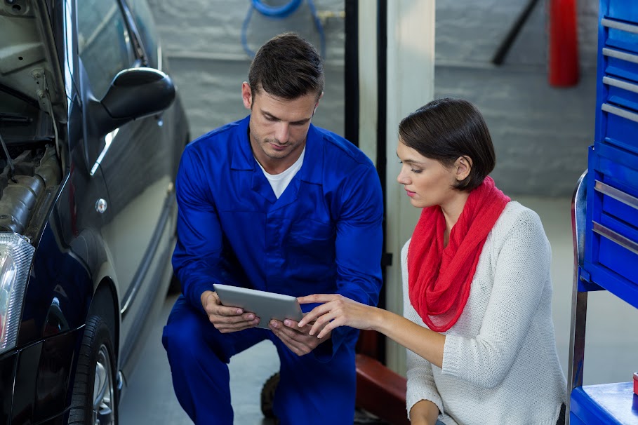 Mechanic using digital tablet with customer in repair garage Car Consulting Experts Sydney